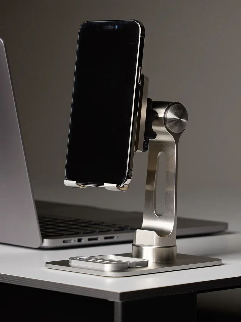 Børstet aluminiumsholder med telefon ved siden af en bærbar computer
